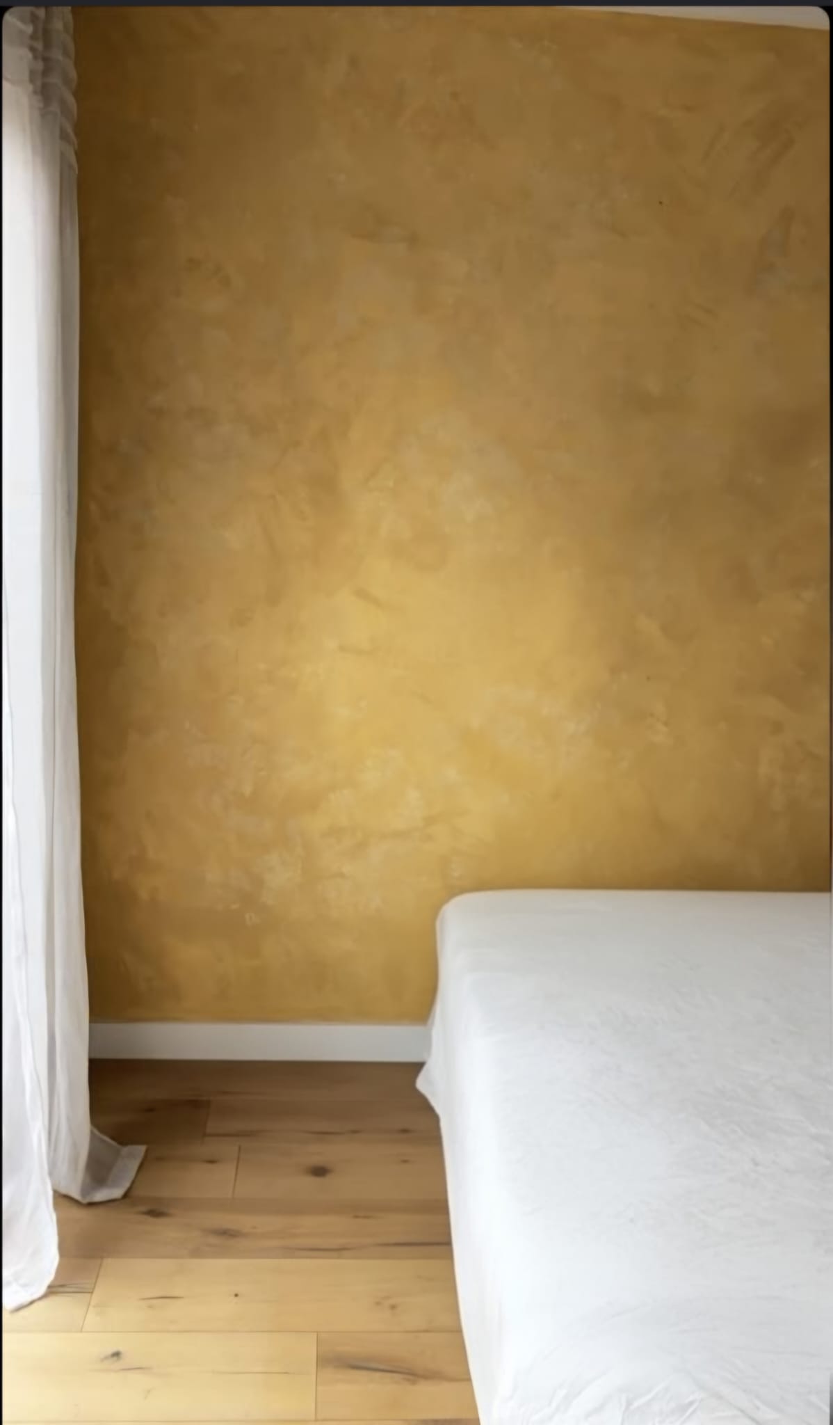 Ochre lime-plaster feature wall finish, bedroom